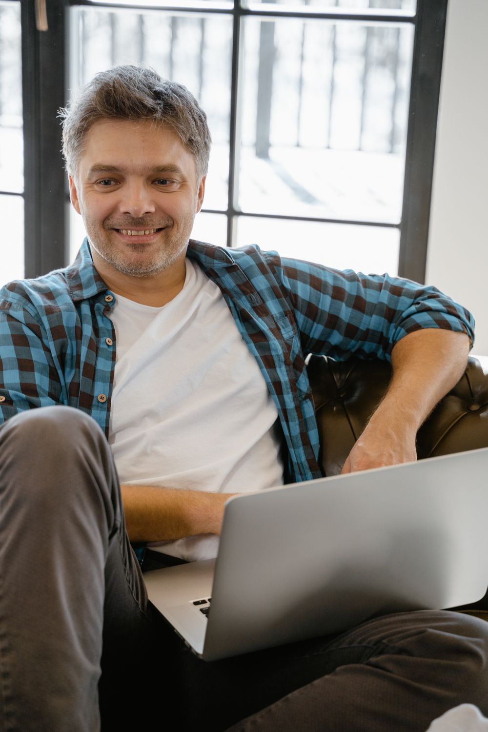 Man smiling while using a laptop at home
